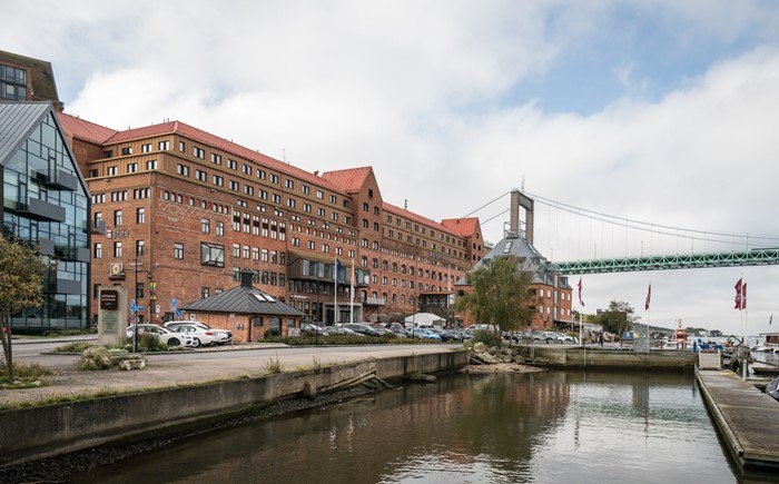 Tegelbyggnader vid vattnet i Klippan med Älvsborgsbron i bakgrunden.
